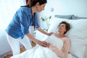 Older adults perform seated and standing exercises with an instructor in a bright assisted living activity room.