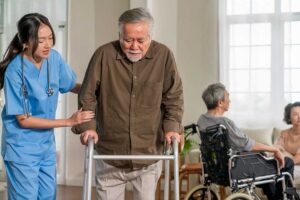 Older adults practice gentle chair exercises with an instructor in a bright assisted living activity room.