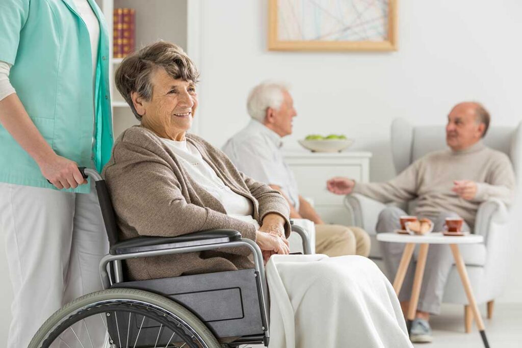 Family member and older adult sitting together during a group activity in an assisted living common room.